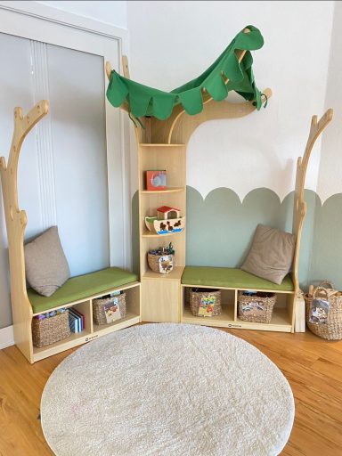 Ecke mit Baumhaus-Möbel, Sicht mit grüner Decke, Sitzflächen und Kisten für Spielzeug.